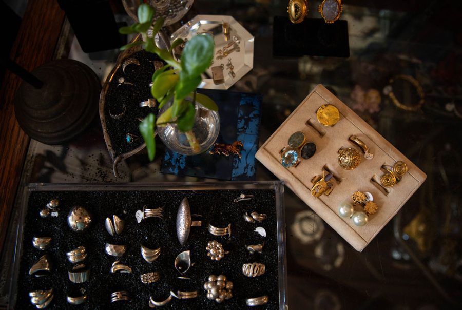 Various rings and earrings displayed in a jewelry case, with a small plant in a glass vase.