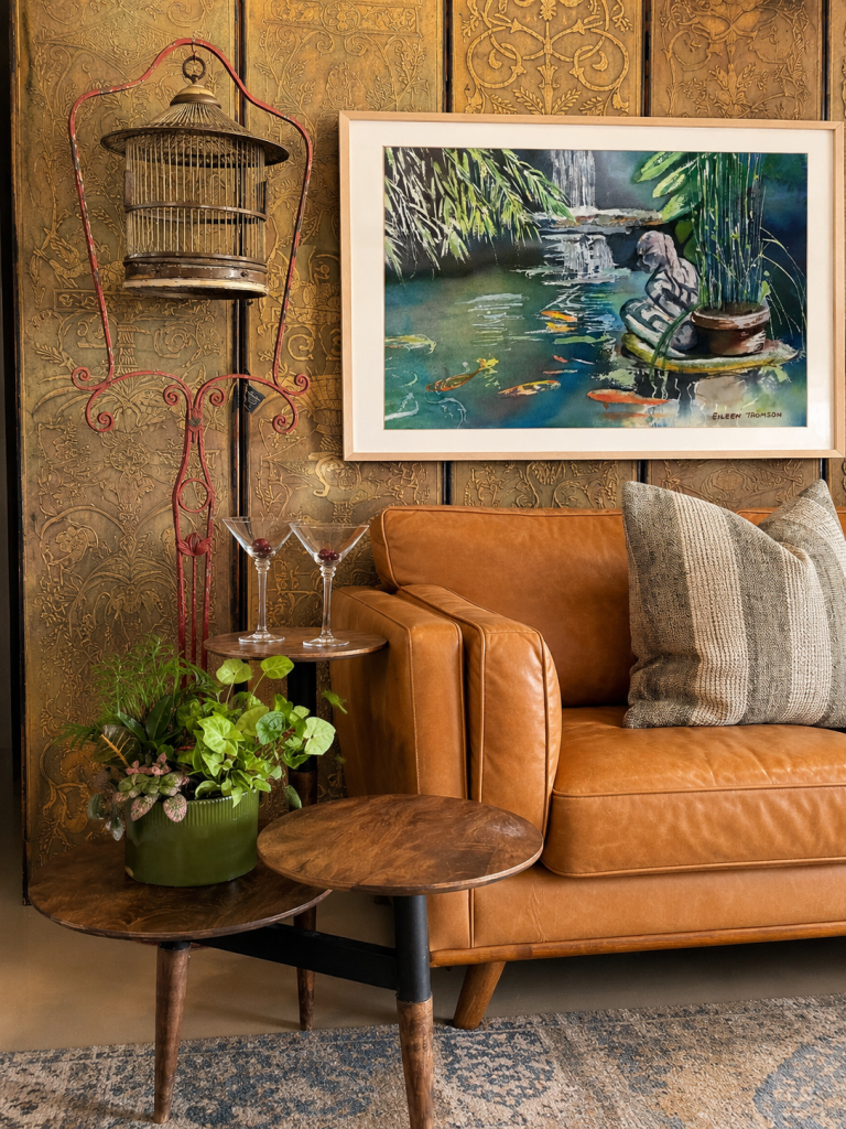 A cozy living space features a brown leather sofa, potted plants, a birdcage, and a colorful painting.