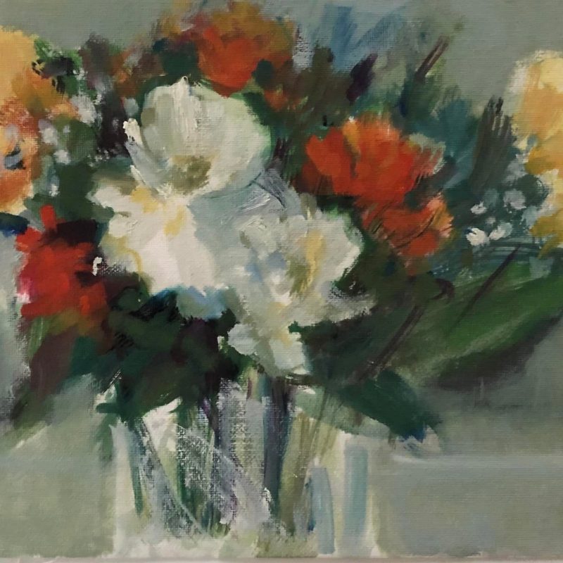 A colorful bouquet of flowers in a glass vase against a soft background.